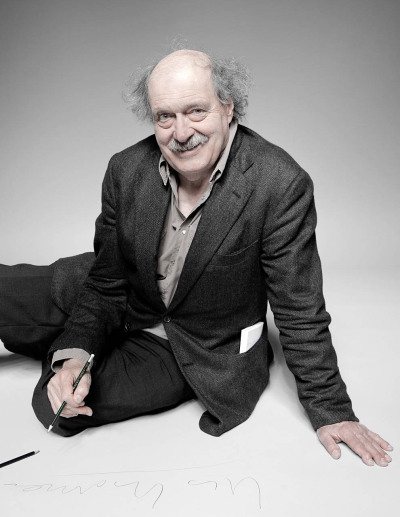 Urs Widmer Schriftsteller - hockt auf dem Boden lacht schreibt seinen Namen auf Papier Foto Farbe - 2012 Foto Peter Koehn